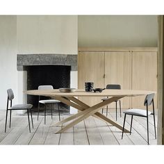 a wooden table with chairs around it in front of a fireplace