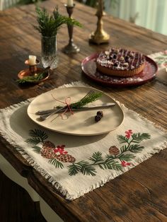 a wooden table topped with plates covered in frosting and pine cone decorations next to candles