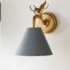 a wall light with a bird on it next to a lamp shade hanging from the wall