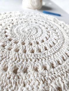 a white crocheted tablecloth with yarn on it and a ball of thread next to it