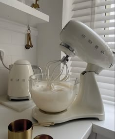 a white mixer and some cups on a counter