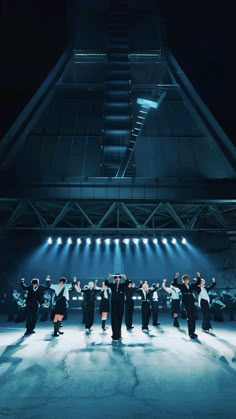 a group of people standing on top of a stage with lights in the dark behind them