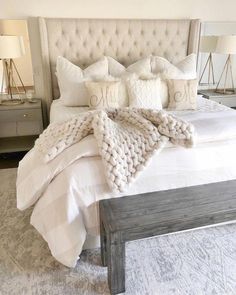 a bed with white pillows and blankets on it