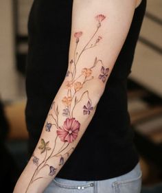 a woman's arm with flowers painted on the back of her arm and shoulder