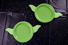 two green plastic plates sitting on top of a black tablecloth covered floor with space in the background