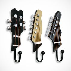 three guitars hang from hooks on the wall