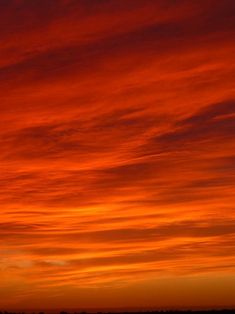 an orange and red sky at sunset with clouds