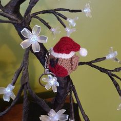 a knitted santa hat on top of a tree branch with white flowers and lights