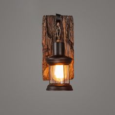 a light that is hanging from the side of a wooden wall mounted fixture with a chain attached to it