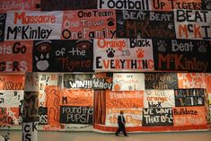 a person walking in front of a wall covered with orange and black signs