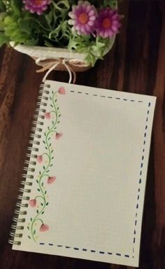 a notepad with flowers on it sitting next to a potted plant