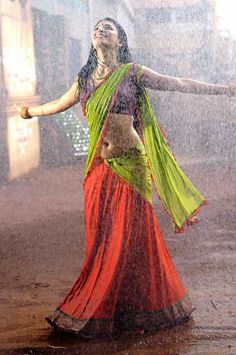 a woman dancing in the rain with her arms outstretched