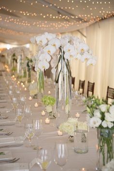 a long table is set with white flowers and candles for a formal dinner or reception