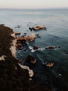 an aerial view of the ocean and rocky coastline