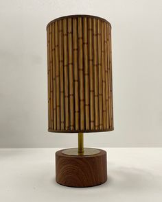 a lamp that is on top of a wooden base and has a bamboo lampshade