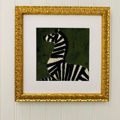 a zebra is shown in a gold frame on the wall next to a green and white striped wall