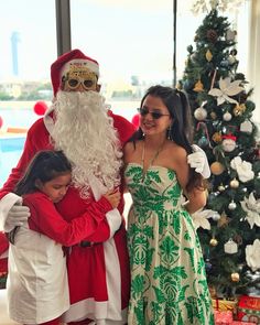 a girl hugging santa claus in front of a christmas tree