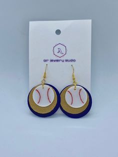 a pair of earrings with baseballs on it in front of a white card board