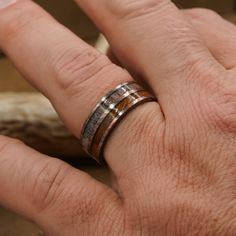 a person's hand with a ring on it and a piece of wood in the background