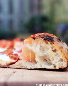 a half eaten pizza sitting on top of a wooden table next to another piece of bread