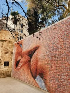 a brick wall with an image of a woman's face on it and trees in the background