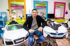 a man sitting on top of two toy cars in a room filled with children's toys