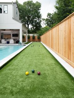 a backyard with artificial turf and pool in the back yard, surrounded by a wooden fence