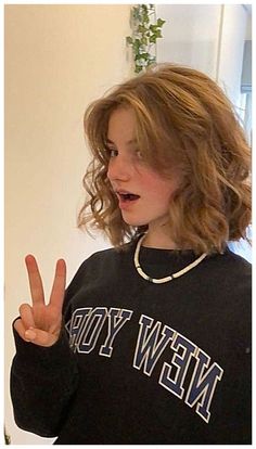 a young woman making the peace sign with her fingers while wearing a new york sweatshirt