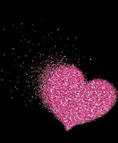 a pink heart is in the dark with lots of sparkles on it's side