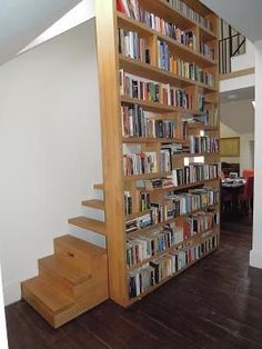 a bookshelf filled with lots of books next to a stair case