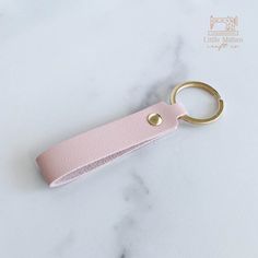 a pink leather keychain sitting on top of a marble counter