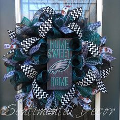 the wreath is decorated with green and black ribbon, which reads home sweet at the front door