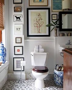 the bathroom is decorated in blue and white with pictures on the wall above the toilet