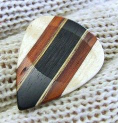 a wooden brooch with black, brown and white stripes is laying on a piece of fabric