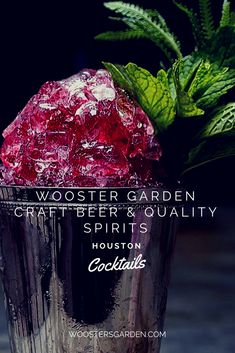 a close up of a drink in a metal cup with ice on the rim and green leaves