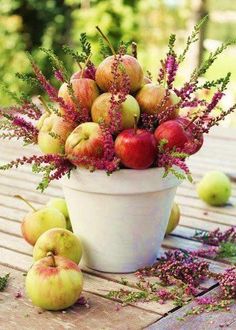 there are two pictures of apples and flowers in the same pot, one has red berries on it