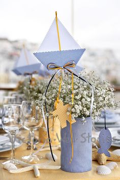 a blue and white striped bucket with flowers in it sitting on top of a table