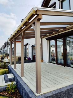 an outdoor patio with wooden posts and white walls