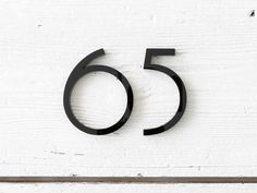 the number fifty five is shown in black on a white painted wood background with an iron ring