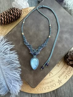 a necklace with a blue beaded pendant on top of a table next to feathers