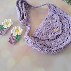 a crocheted purse, hair clips and flower brooch are laying on a table