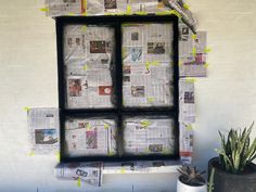 a window that is covered in newspaper next to a potted plant