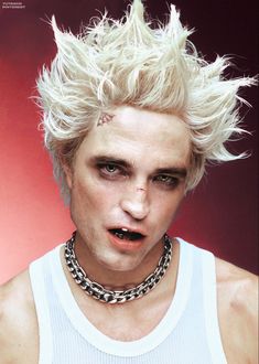 a man with blonde hair and piercings on his face wearing a chain around his neck