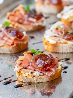 small sandwiches with meat and cheese are on a metal tray, ready to be eaten