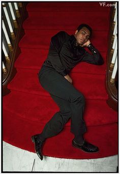 a man laying on top of a red carpeted stair case