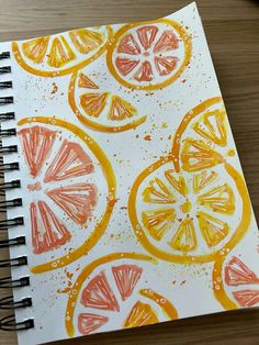 an art journal with oranges and lemon slices painted on it, next to a pen