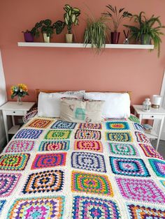 a crocheted blanket on top of a bed in a room with pink walls