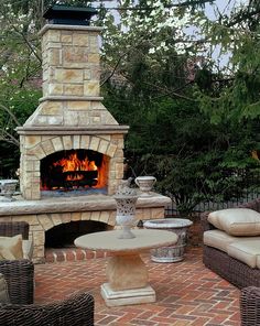 an outdoor fireplace with wicker furniture around it