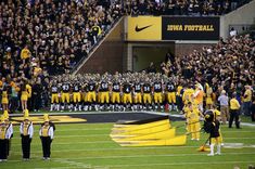 a group of people standing on top of a football field next to each other in front of a crowd