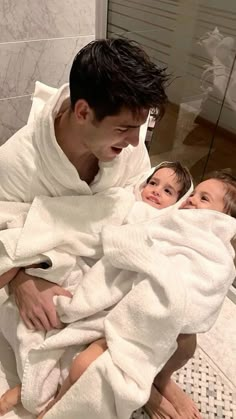 a man holding a baby wrapped in a white towel while standing next to a woman